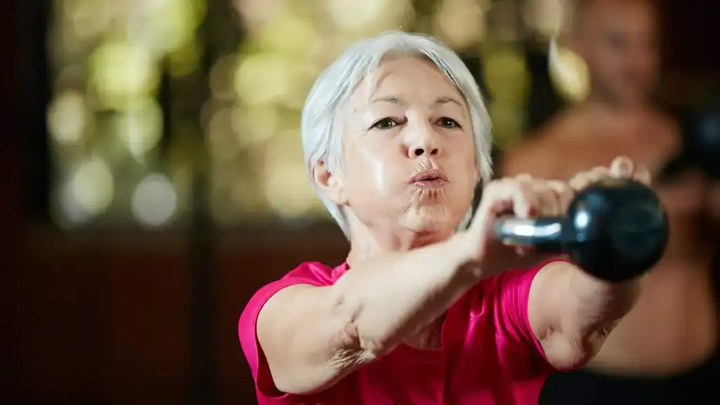 Older woman doing weight training Suffolk to help her strength and longevity 
