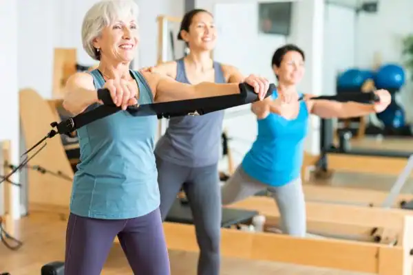 Toning Arms After 60: Empowering Womens Fitness Through Effective Weight Training 2 older woman doing weight training Suffolk and resistance in the gym to tone upper arms