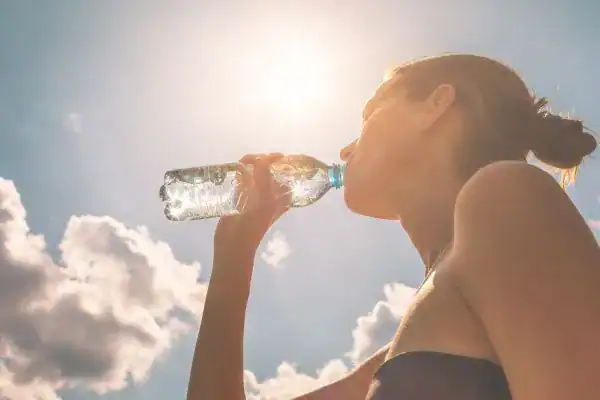 Hydration: The Secret Ingredient for a Toned Stomach and Enhanced Fitness 3 Image of woman drinking water to hydrate Suffolk after run.