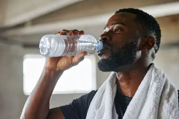 Hydration: The Secret Ingredient for a Toned Stomach and Enhanced Fitness 1 Image of man drinking water to improve hydration Suffolk after work out.
